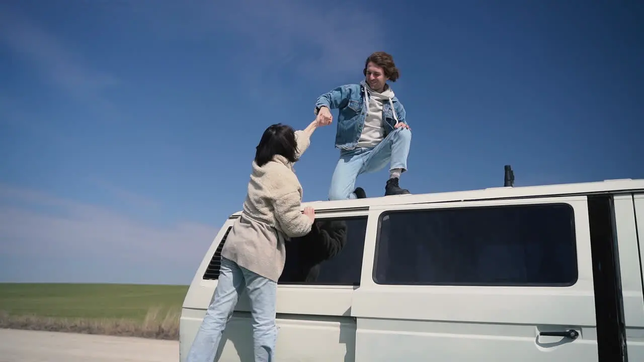 Young Boy Helps His Girl Friend Onto The Roof Of The Caravan