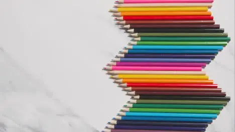 Coloured Pencils Arranged In A Symmetrical Pattern On White Marble Background 