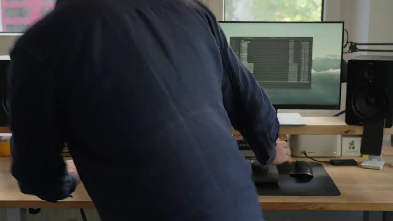 Enter the dynamic world of a ponytailed man working diligently at his computer desk