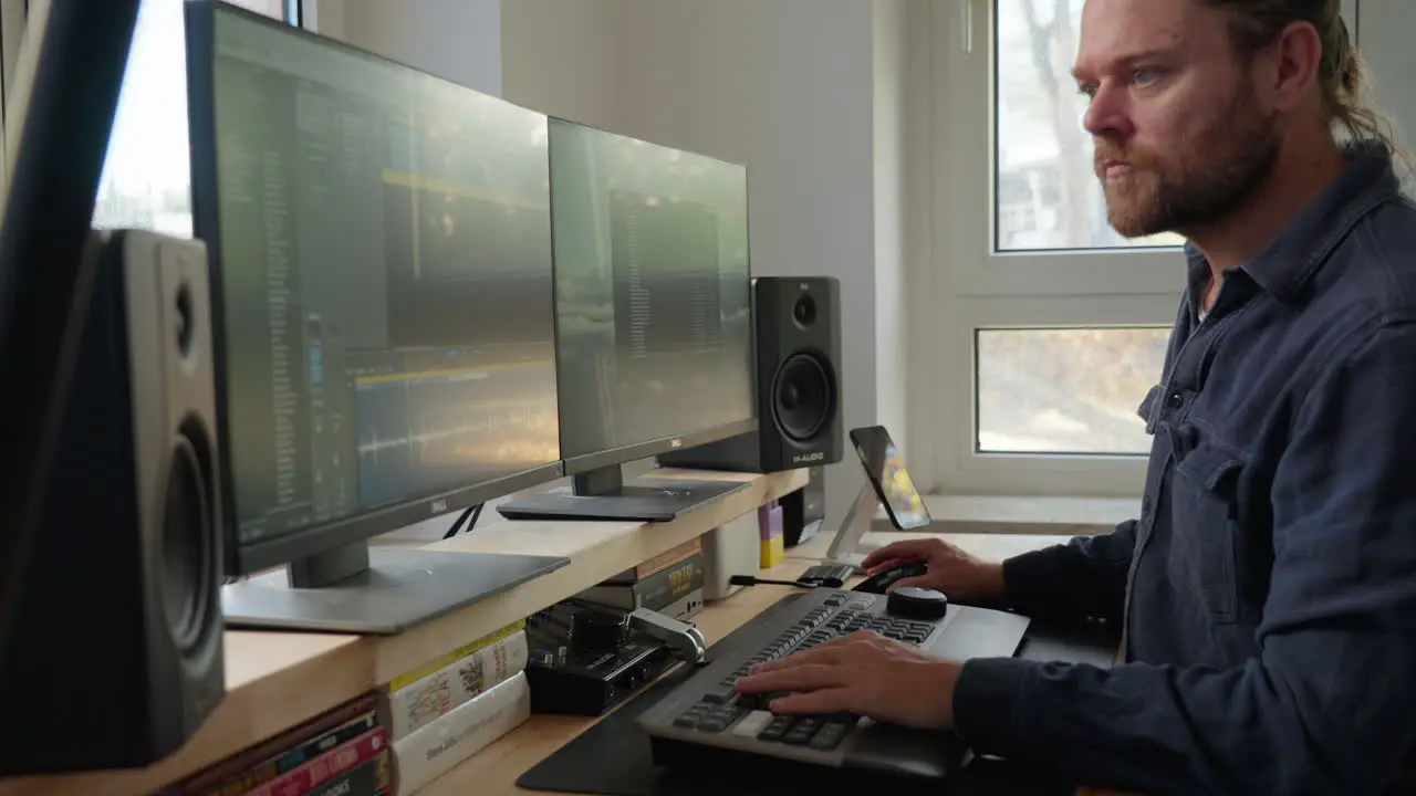 Engage in the focused work environment as a man with a ponytail diligently operates a computer at his desk