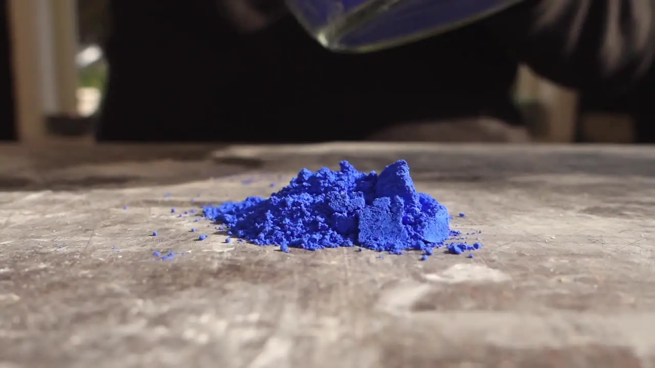 Artist prepering blue powder pigment on table in workshop closeup