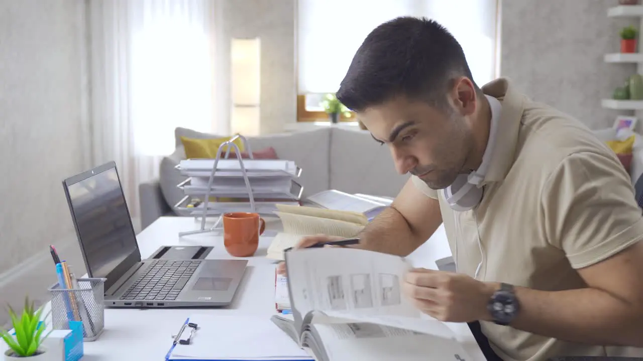 Student looking at books and laptop at home