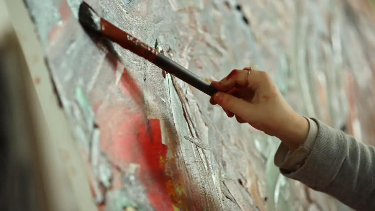 Kid painter hand making brush stroke on canvas in art studio