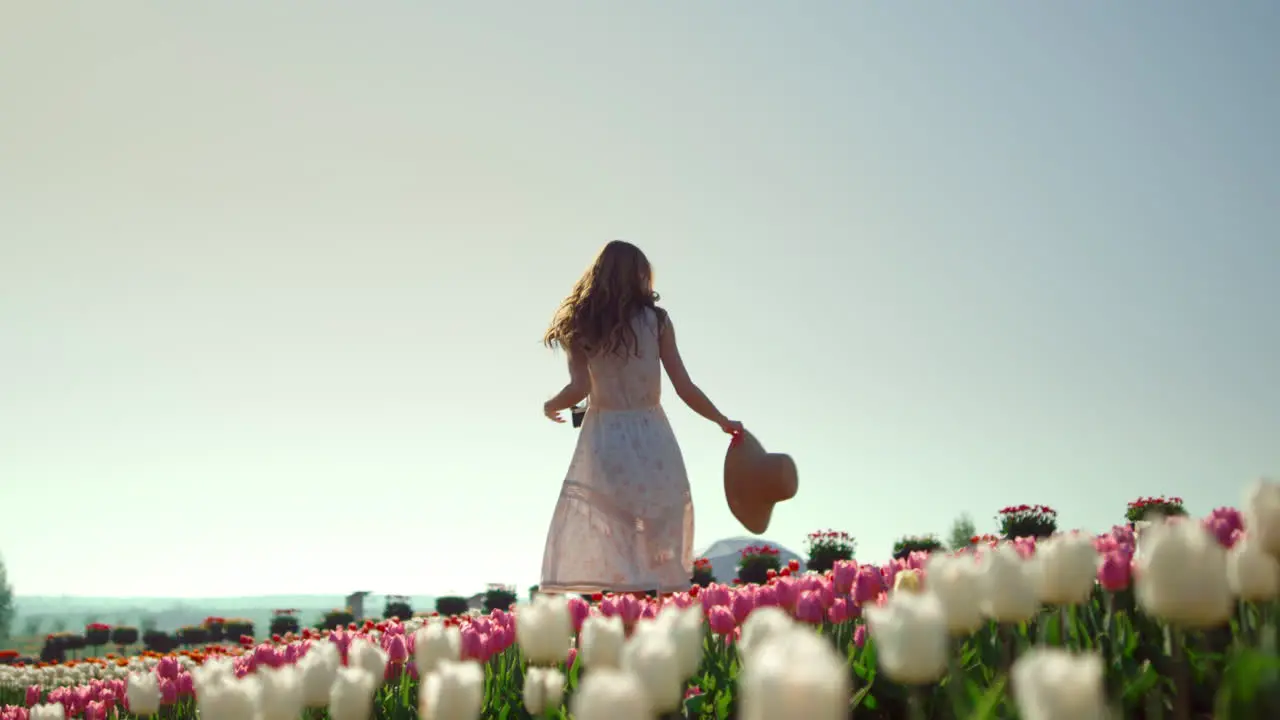 Happy girl turning around in tulips gardenCreative young woman enjoying flowers