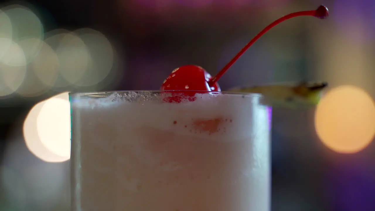 piña colada detail shot of top garnish cherry pineapple spinning in bar lights