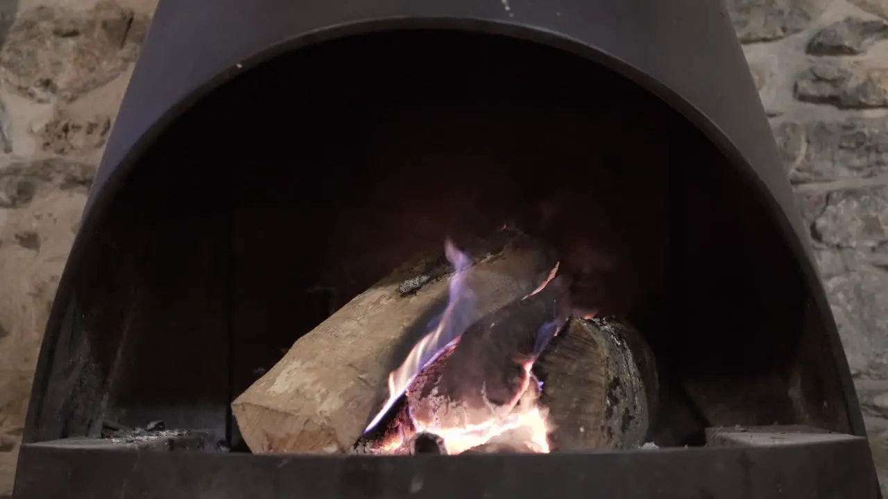 4K clip of a beautiful wood fire burning inside a traditional rural black l fireplace in a winter house