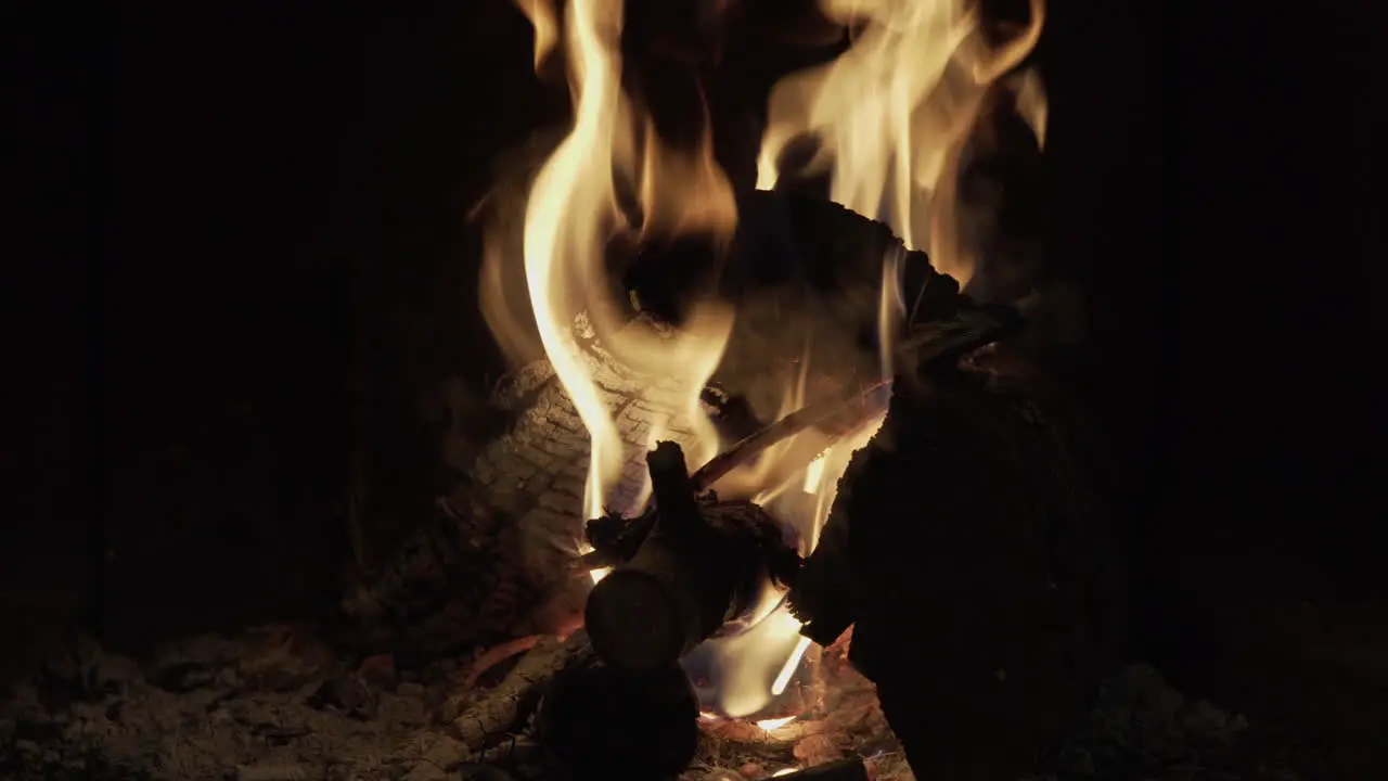 4K close up clip of a dark and warm wood fire burning inside a traditional rural black fireplace in a winter house