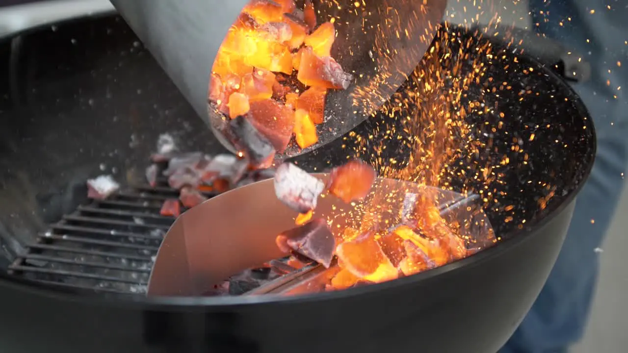 Flaming coals are added to charcoal grill slow motion