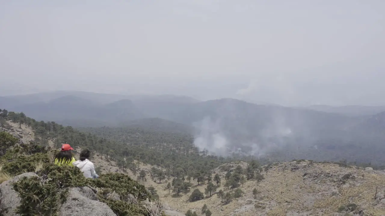 A closeup shot of Hispanic hikers sitting on top of the Tlaloc Mount on a gloomy day in Mexico fire in the forest