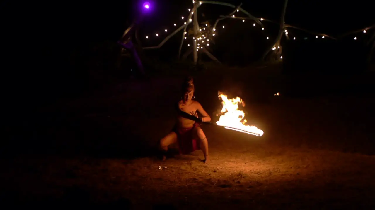 Asian woman in tribal attire artistically swinging flame sword during jungle worship ceremony