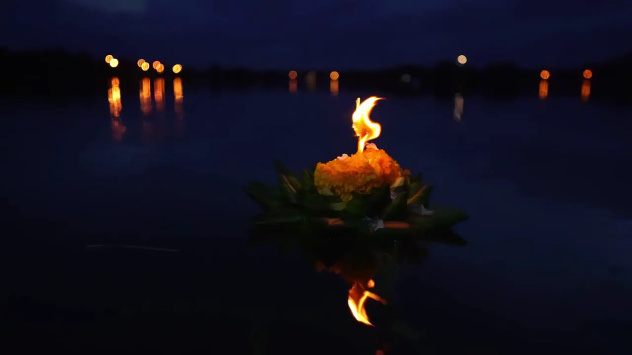 Loy Krathong Festival Beautiful Krathong made from banana leaves and orange flowers with a burning candle top on the dark blue water