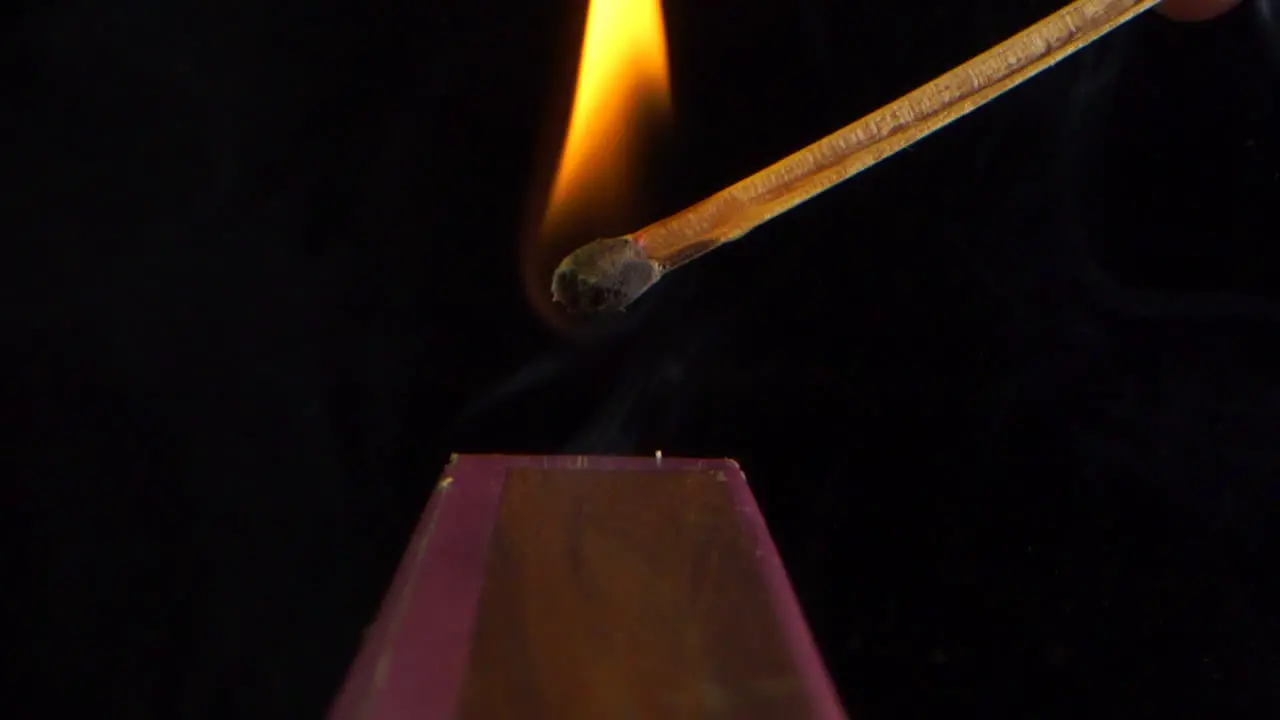 Ignition and burning in slow motion of a match on the side of the box black background