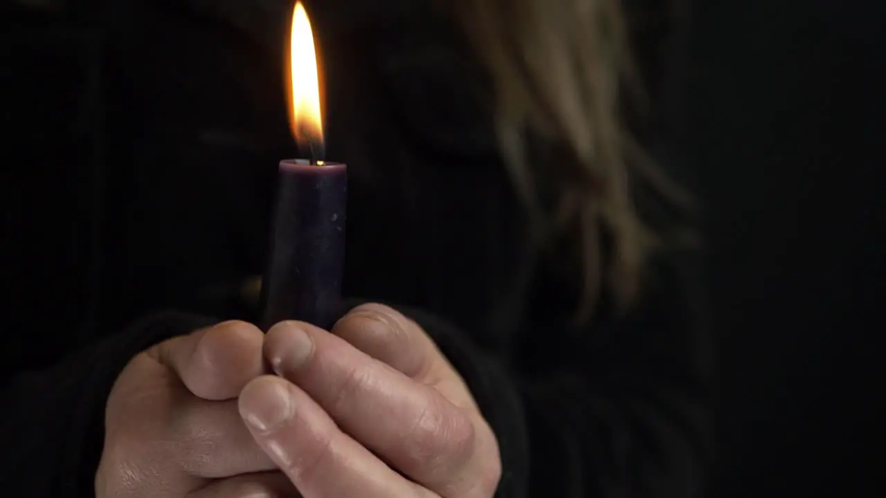 Woman holding a long candle for vigil on dark background medium shot