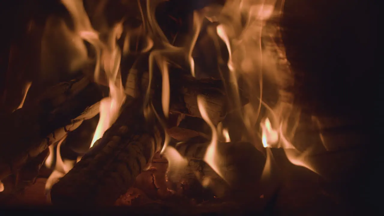 Charred fire logs with glowing embers and hot dancing flames in campfire burner