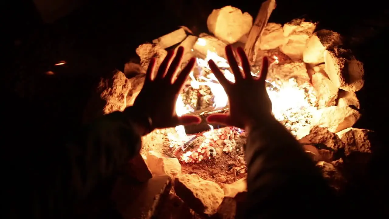 Man warming hands by cozy bonfire during cold winter in Europe zoom out