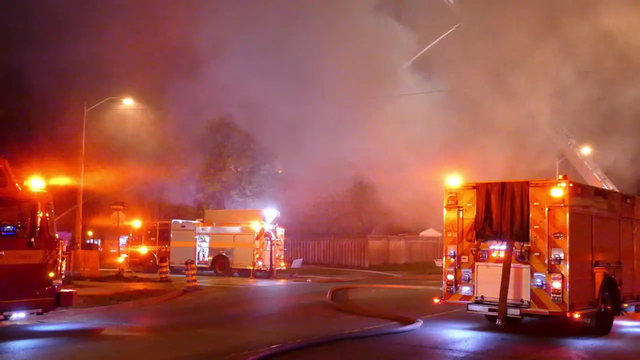 Group of fire engine trucks at fire scene with massive smoke handheld view