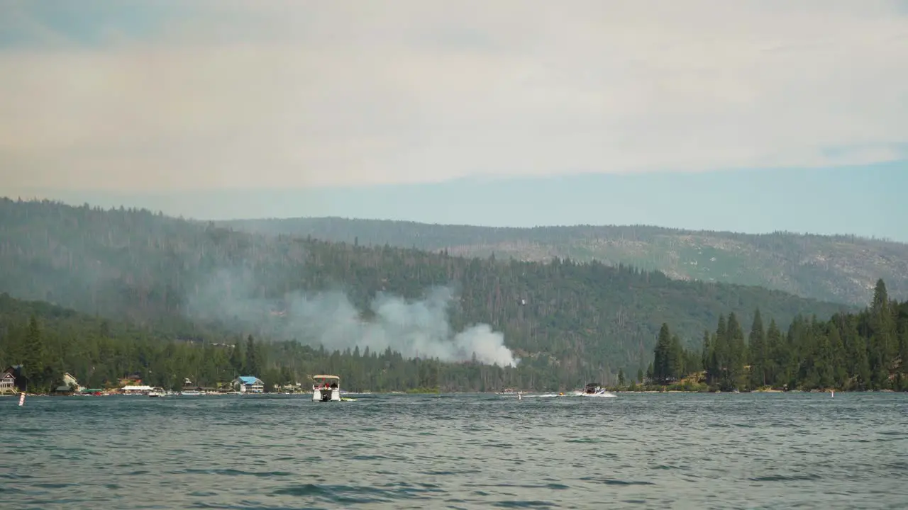 California Wildfire mountain burns on edge of lake helicopter drops water on smoke plume