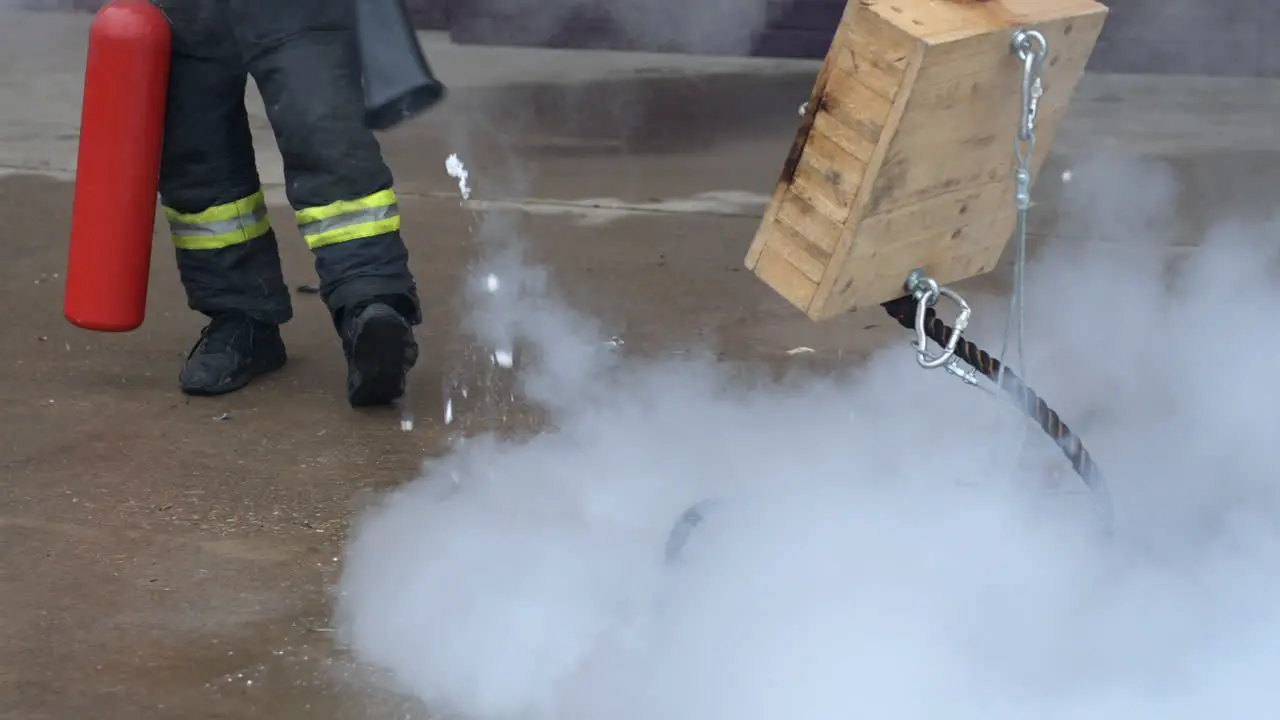 Unrecognizable fireman using a fire extinguisher to extinguish burning rope