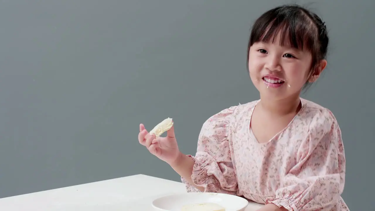 Happy little Asian girl rubs her eyes smile and enjoy eating crispy butter toast at home