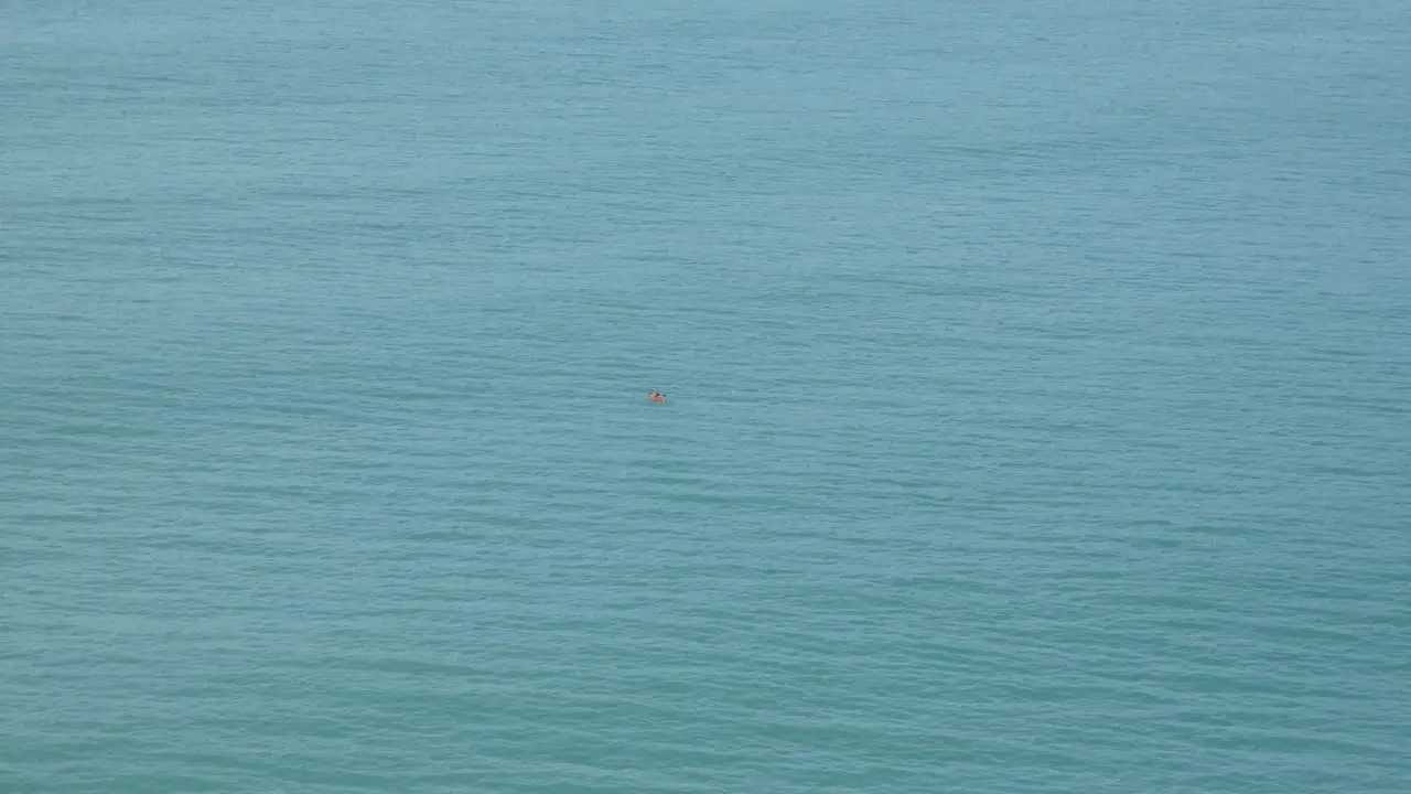 Lone kayaker paddles on calm ocean near harbor entrance Lyttelton Harbor New Zealand