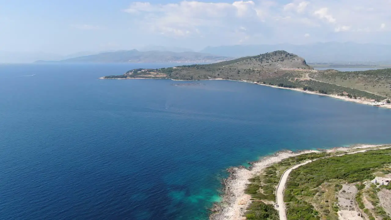 Drone view in Albania flying over blue water sea next to green mountains landscape sunny day in Ksamil