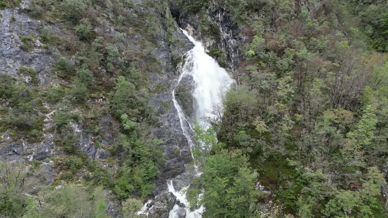 Waterfall cascading though trees Lake Bohinj Slovenia drone aerial push in shot