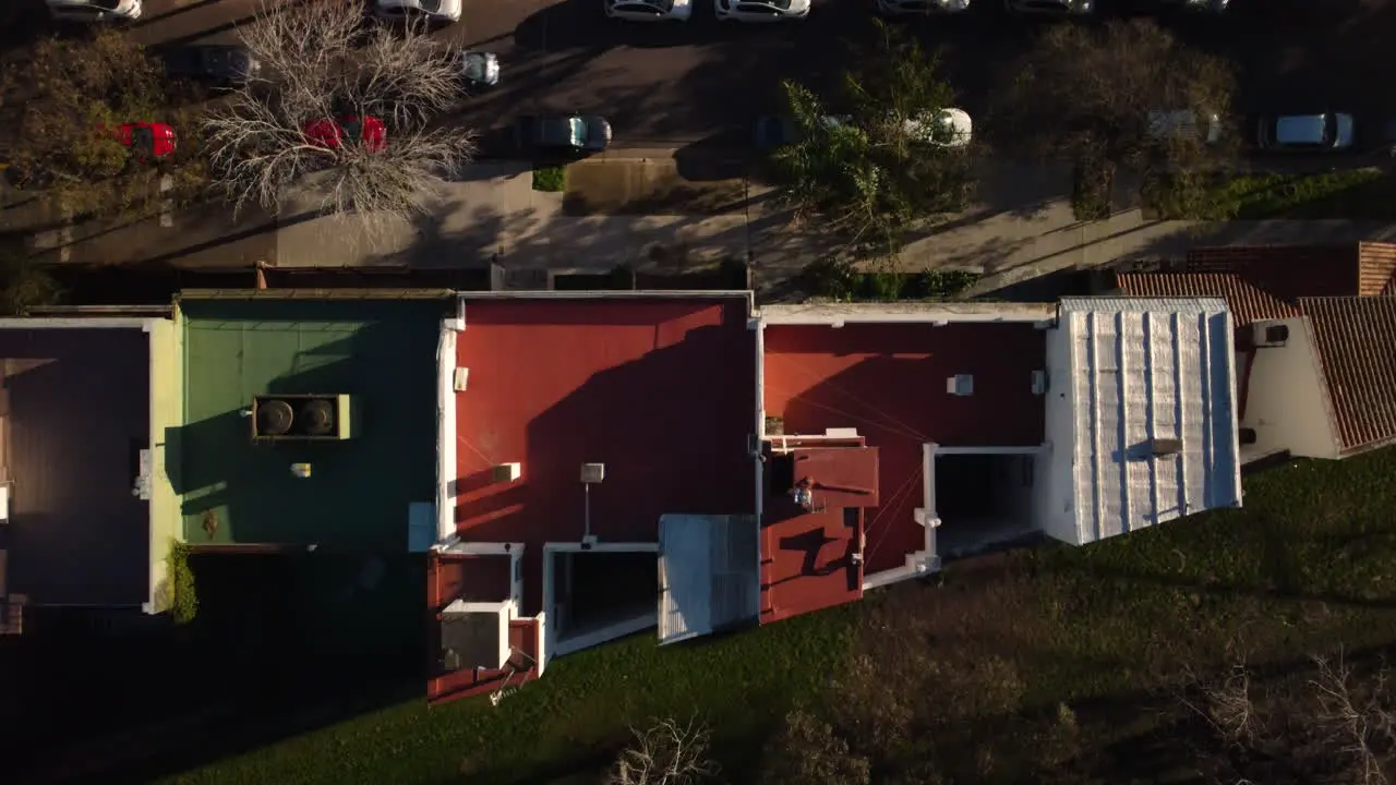 The drone flies from the road towards the park past the roof of the house the car passes along the road