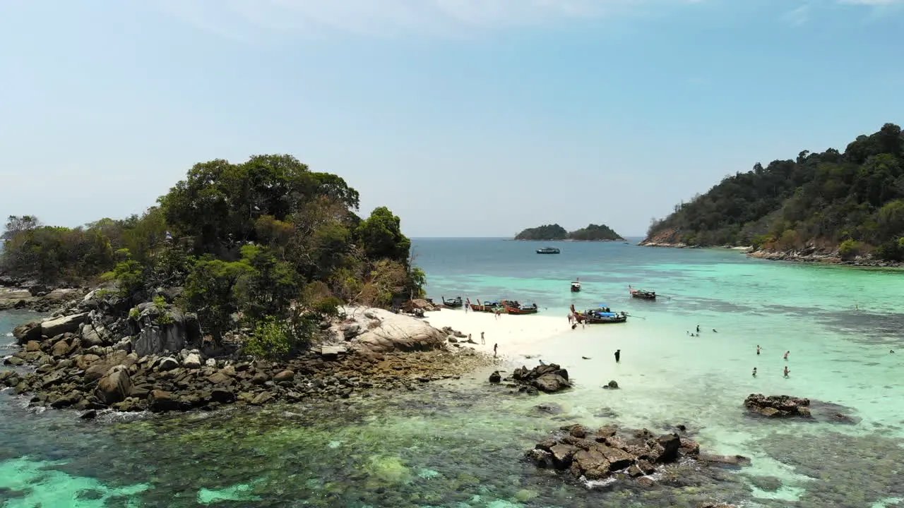 Aerial view of a small island on a paradisiac place with groups of people enjoying the beach