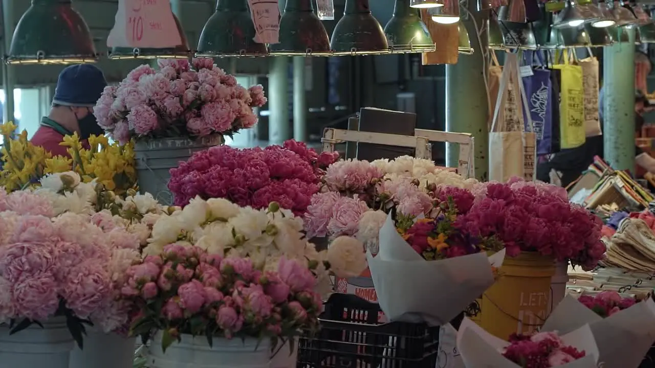 Slow motion shot of a beautiful flower stall inside of the famous tourist attraction of Pike Place Market where tourists and locals come to buy flowers in Seattle Washington USA