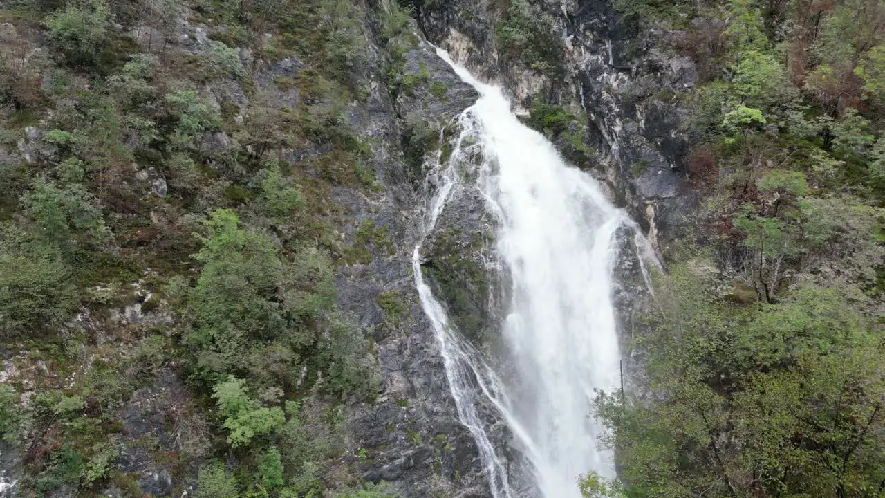 Push in shot Waterfall cascading though trees Lake Bohinj Slovenia drone aerial view