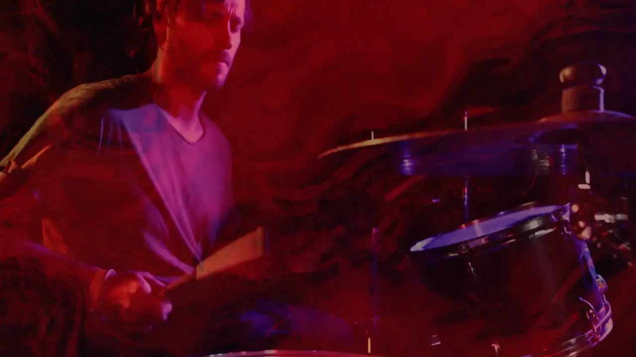 Animation of glowing red lights over mid section of caucasian man playing drums