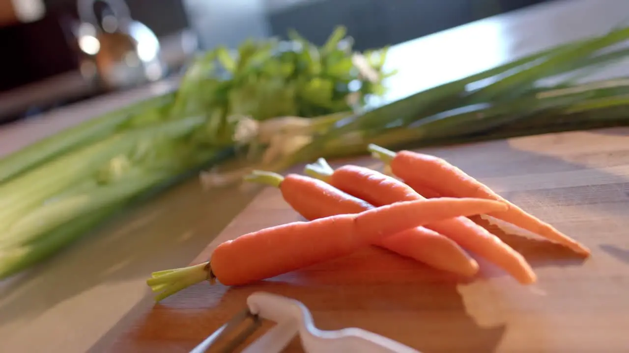 Organic vegetables and peeler on countertop in sunny kitchen slow motion