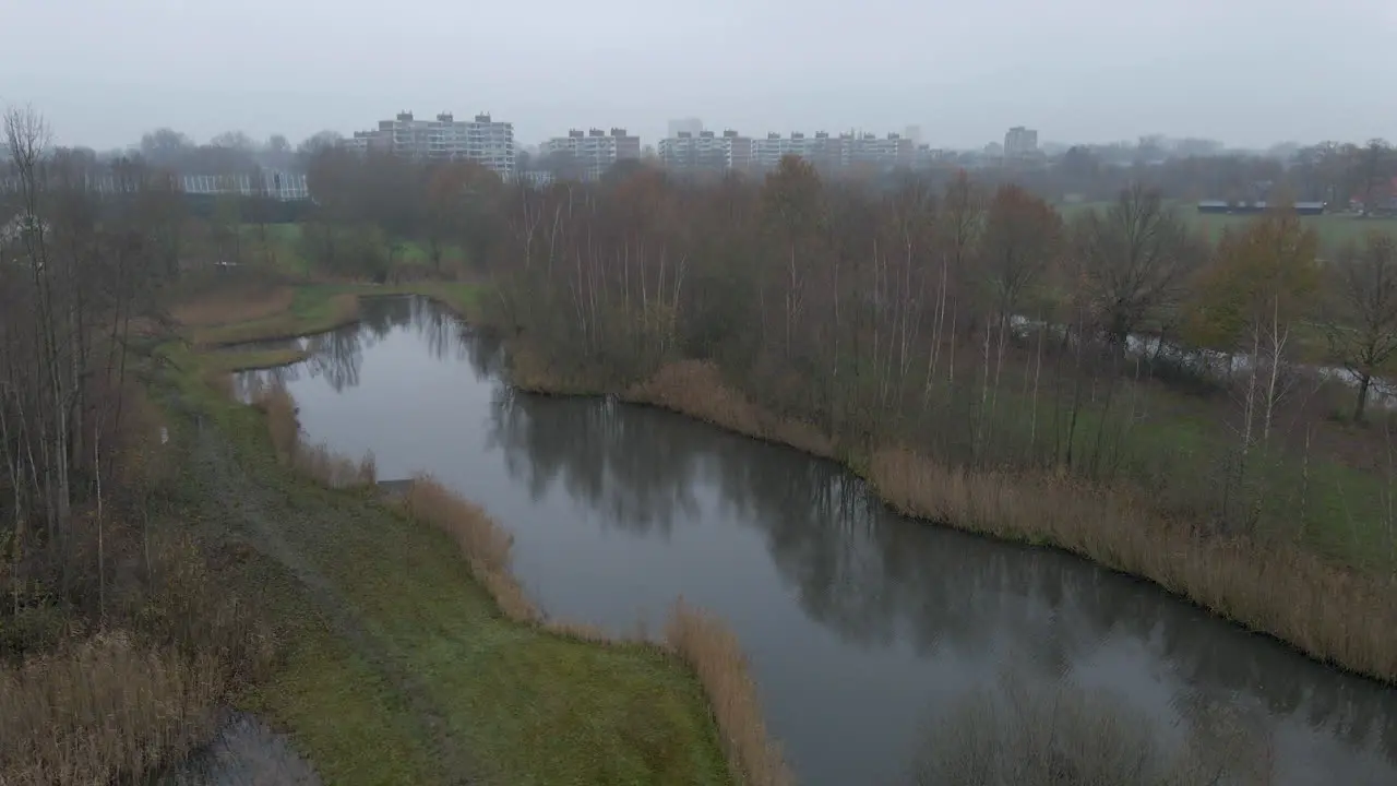 Jib up of beautiful small natural park with a city skyline in the background