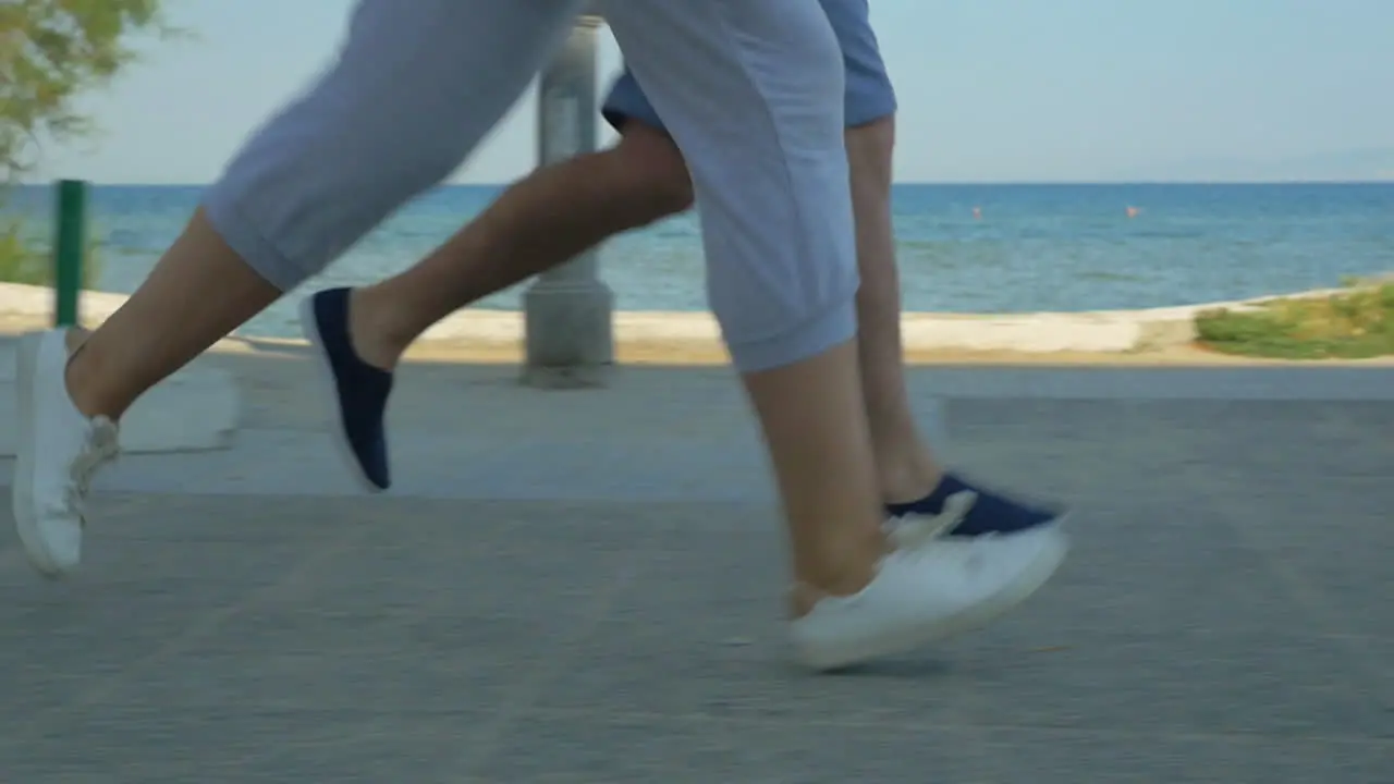 Two people running along the sea on road