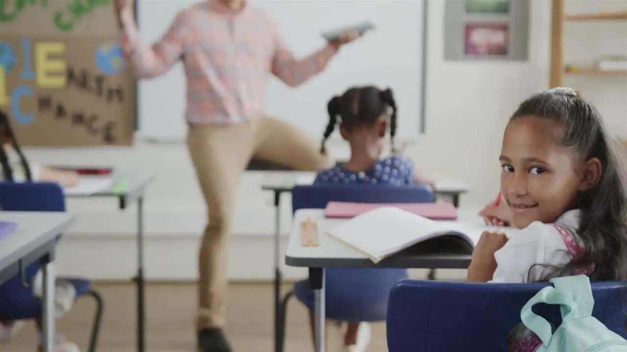 Portrait of happy diverse schoolchildren and male teacher with tablet in classroom in slow motion