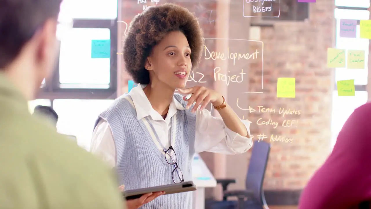 Biracial creative businesswoman with tablet in casual meeting with diverse colleagues slow motion