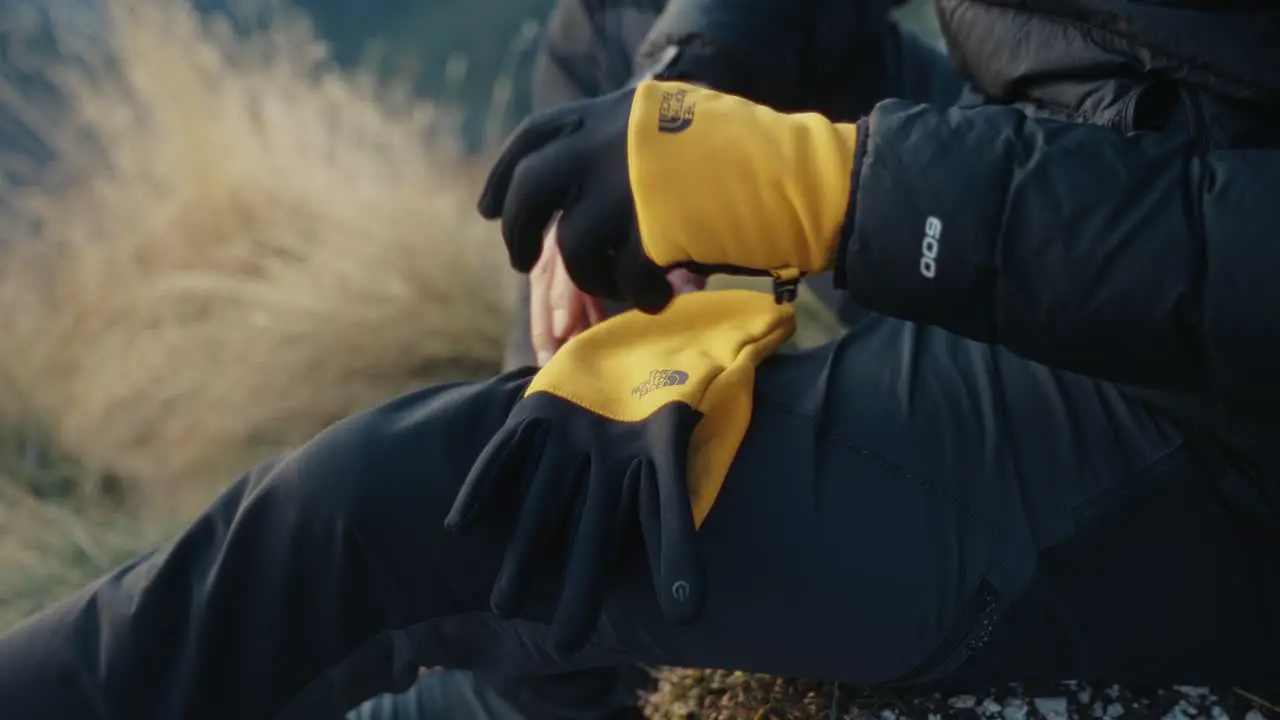 Putting on gloves in the mountains during a hike at sunset