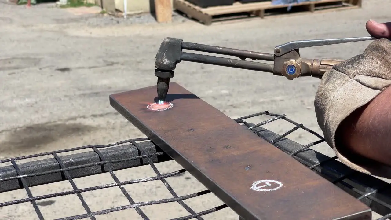 Heat shimmering off a gas welding torch as it cuts a hole in a steel plate