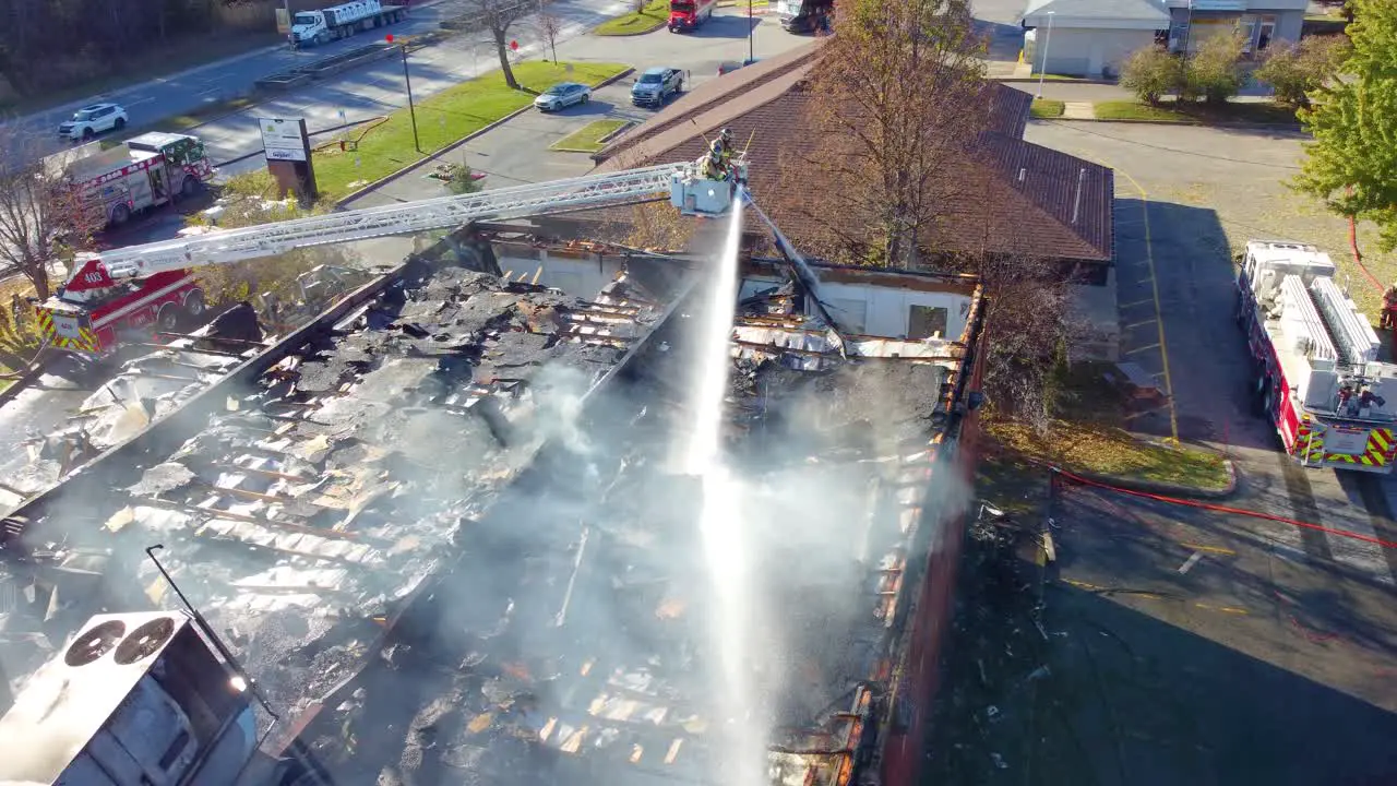 Two Hoses Simultaneously Putting Out Smoking Roof of Large Building Wide Aerial