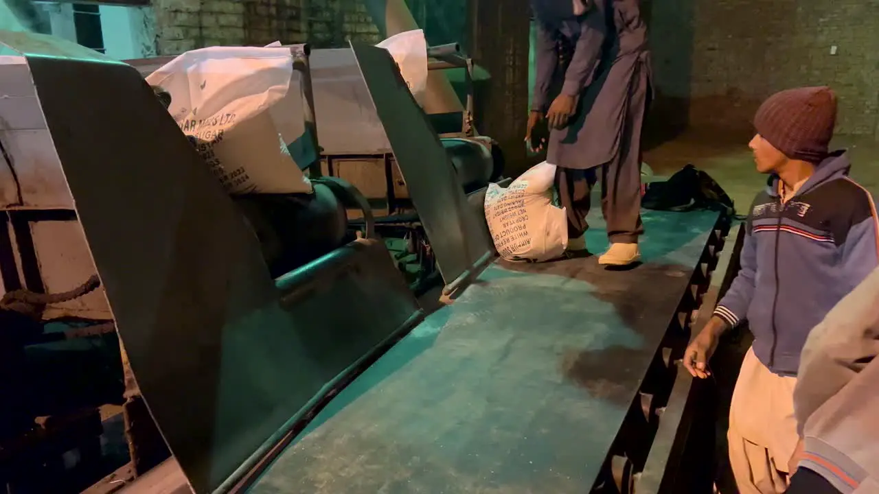 Labors picking up sugar sacks from the production line