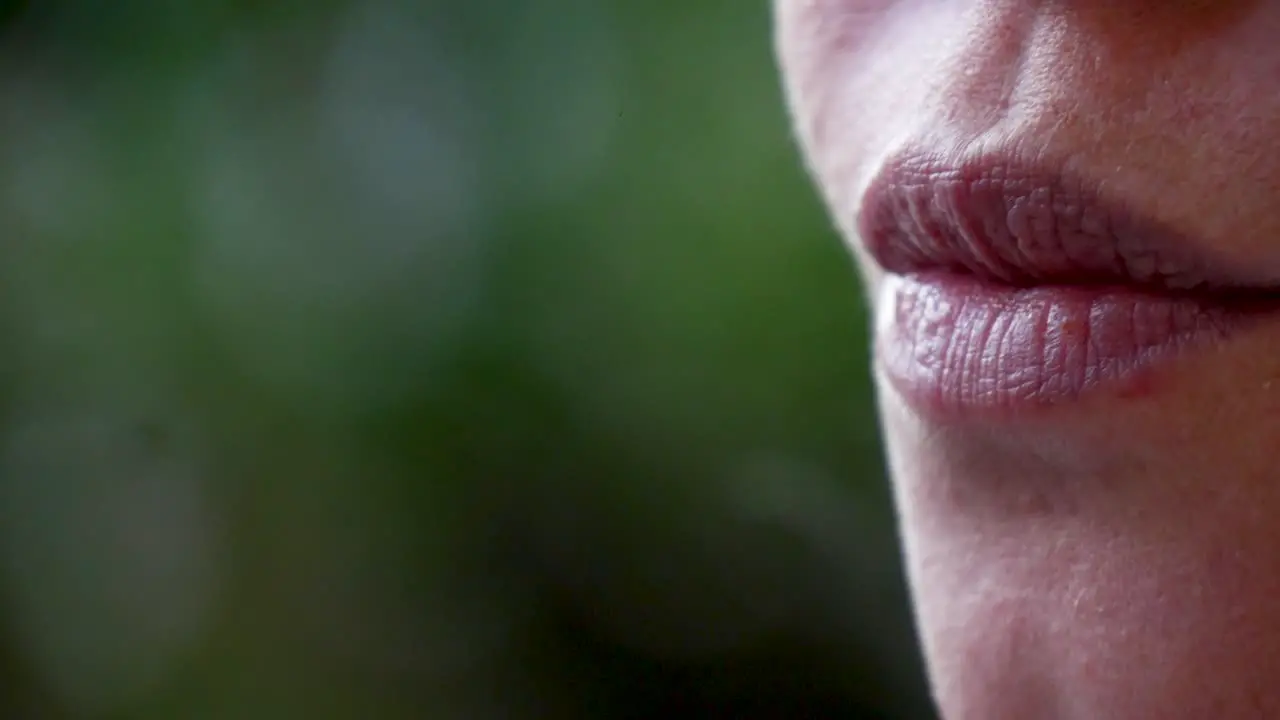 An extreme close up of a beautiful woman smoking a cigarette outdoors