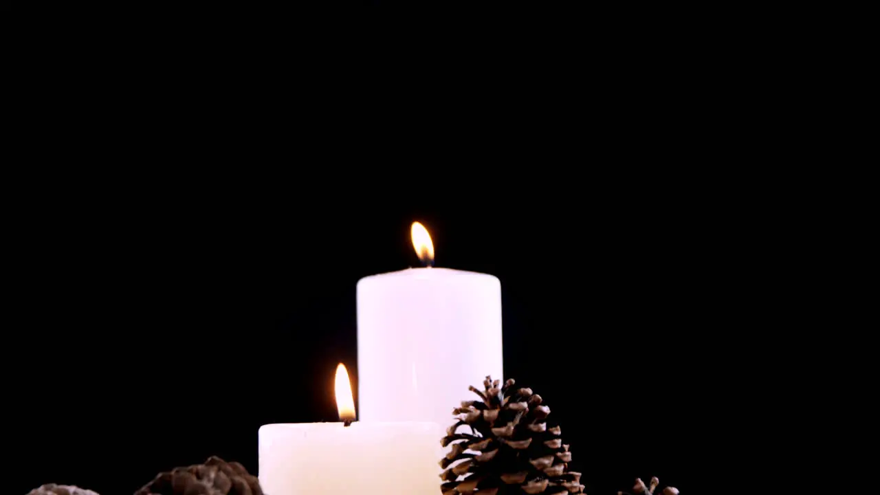 Burning candles and pine cones against black background 4k