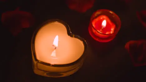 Overhead Shot Of Romantic Heart Shaped Lit Red Candles On Background Covered In Rose Petals