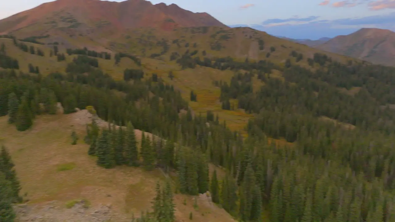 Aerial in the Colorado Rocky Mountains with a pan left to reveal sunset over the mountains