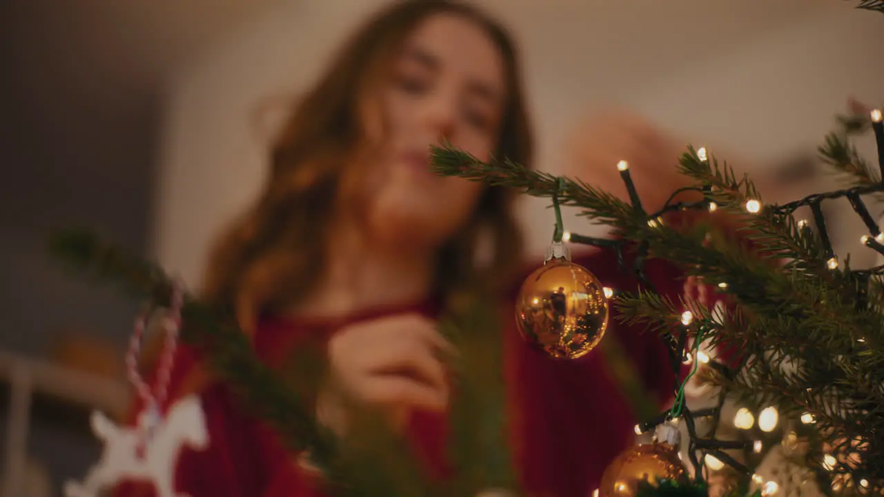 Woman tying bauble while decorating Xmas tree