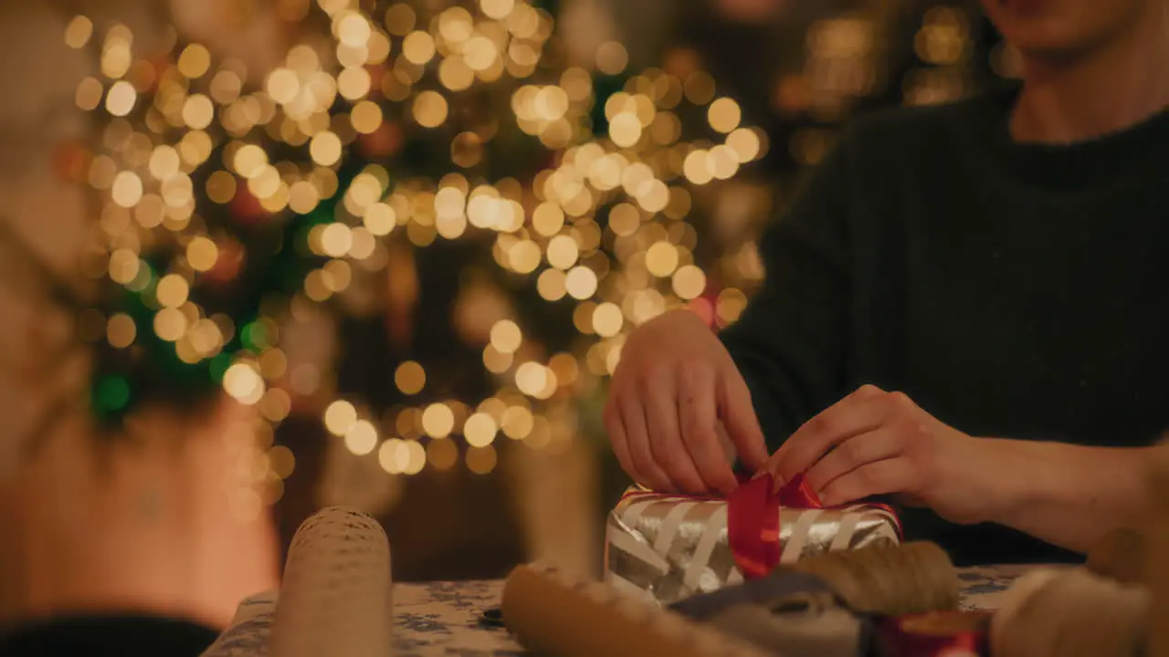 Man tying ribbon to gift box at home