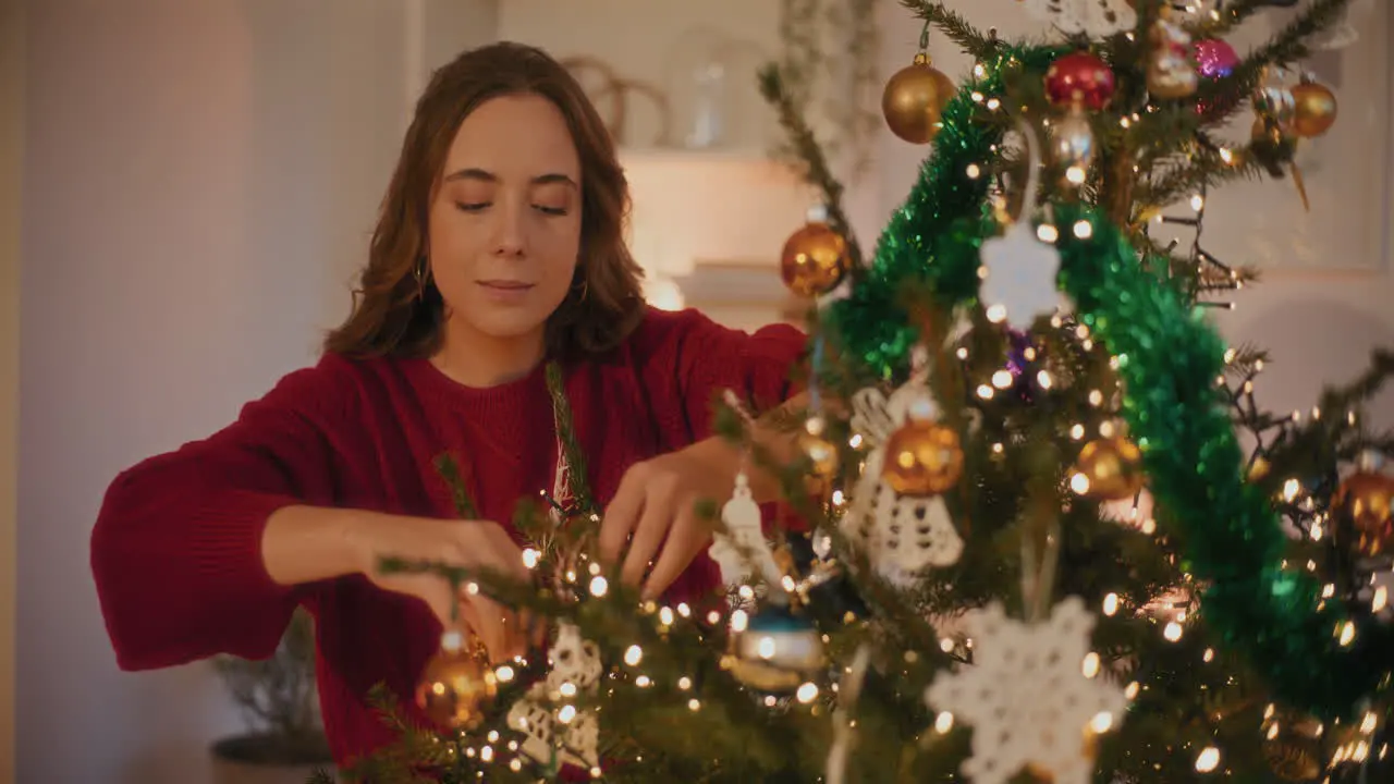 Woman tying Christmas ornaments on tree