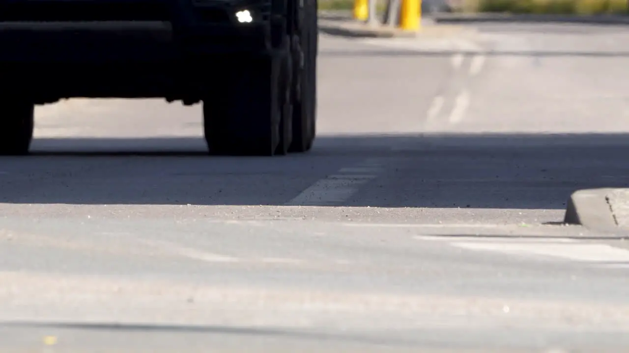 The low angle captures a car's wheel on a concrete road highlighting the contact point between tire and pavement