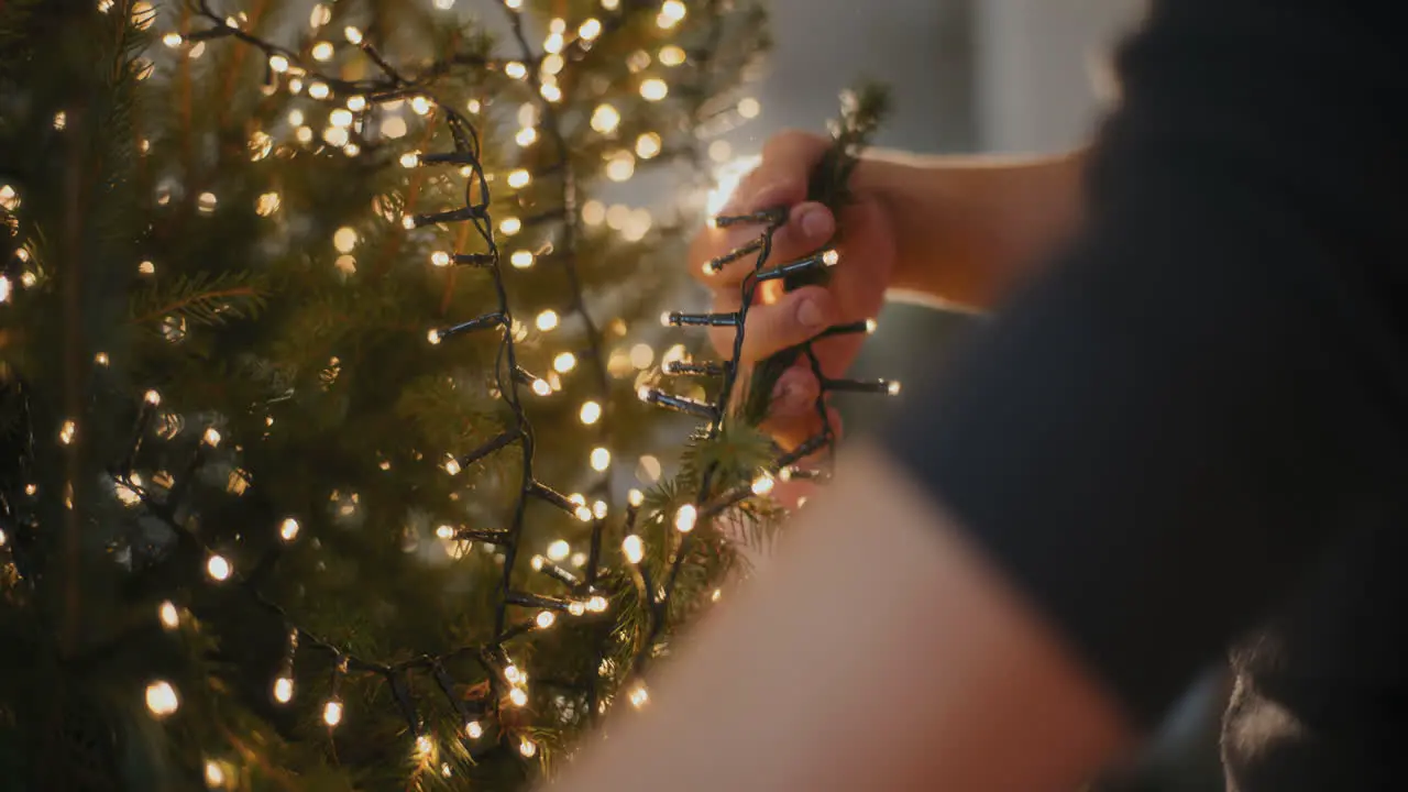 Man with glowing led lights decorating Christmas tree