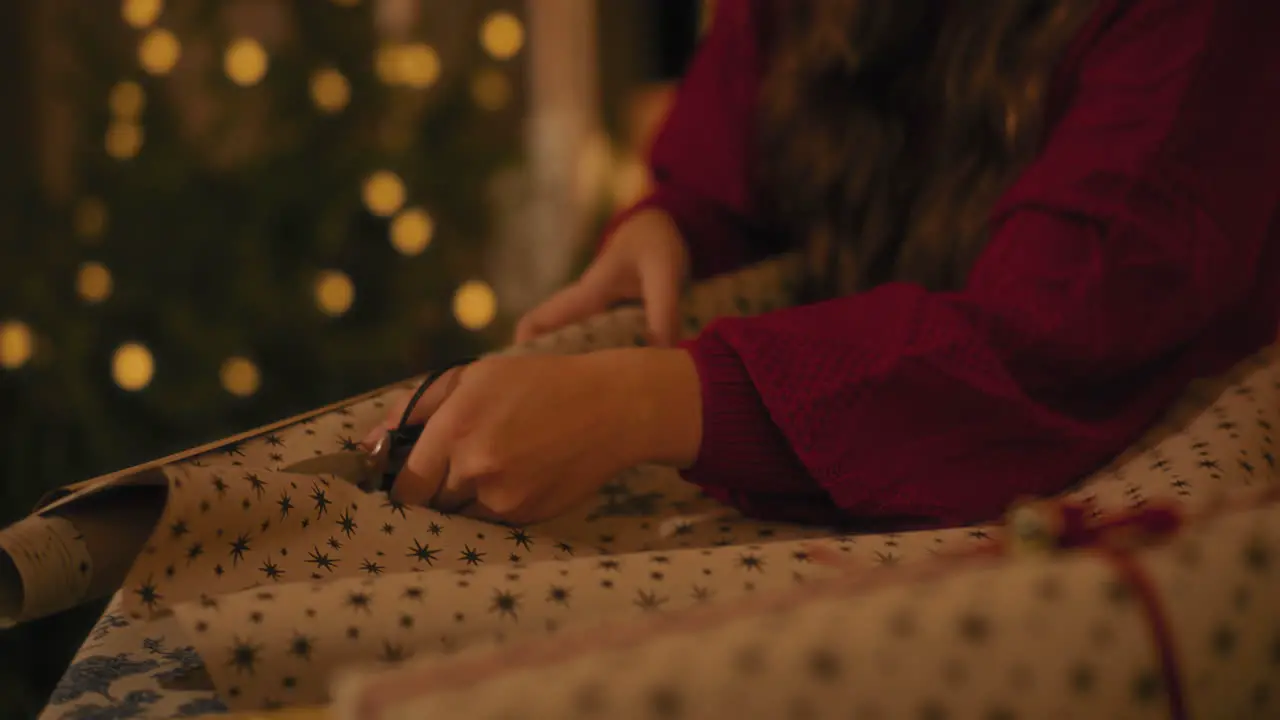 Woman cutting paper while wrapping gift